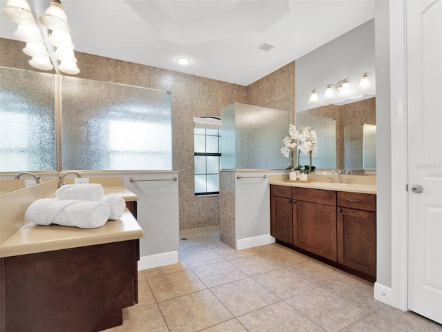 bathroom featuring tile patterned flooring, vanity, tile walls, and walk in shower