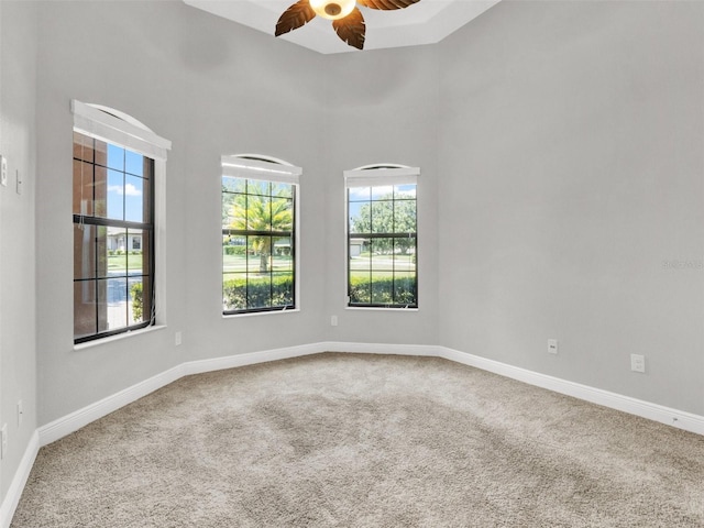 unfurnished room featuring carpet, ceiling fan, and a towering ceiling