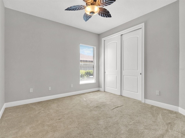 unfurnished bedroom featuring ceiling fan, a closet, and light colored carpet