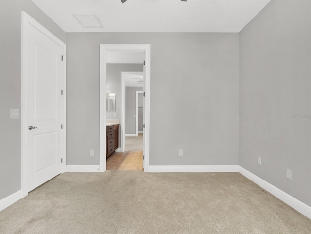 unfurnished bedroom with ceiling fan, light colored carpet, and connected bathroom