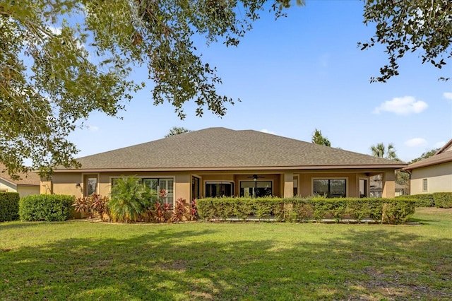 rear view of property with ceiling fan and a yard