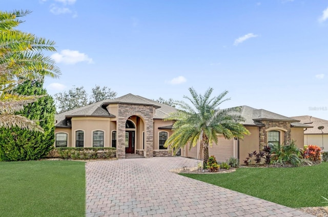 view of front of property with an attached garage, stone siding, decorative driveway, stucco siding, and a front lawn