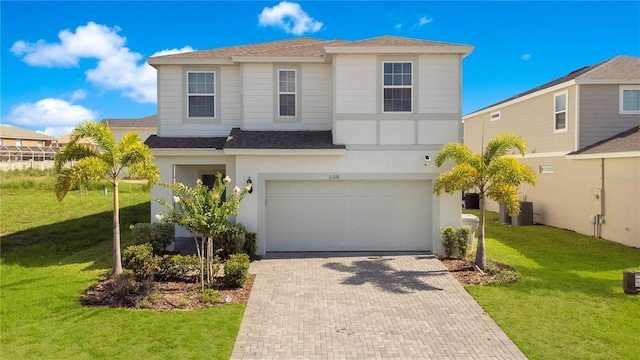 view of front of home with a garage, cooling unit, and a front lawn