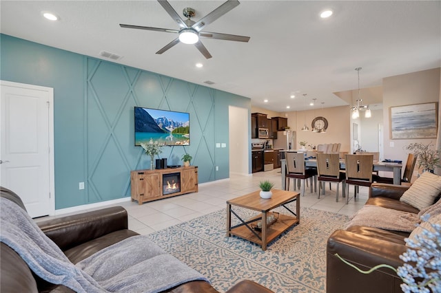 tiled living room with ceiling fan with notable chandelier