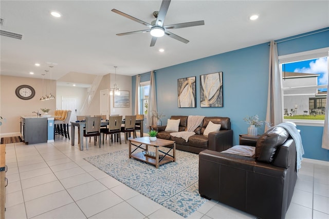 living room with light tile patterned flooring, ceiling fan with notable chandelier, plenty of natural light, and sink