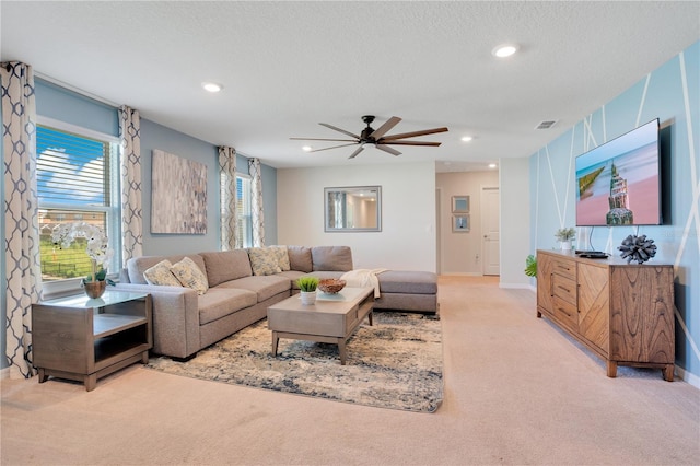 living room featuring ceiling fan, light colored carpet, and a textured ceiling