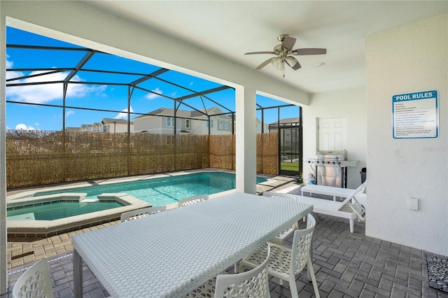 view of pool featuring ceiling fan, glass enclosure, a patio area, and an in ground hot tub