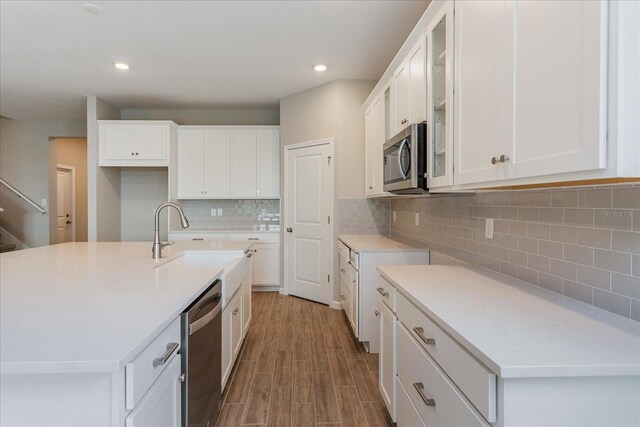 kitchen featuring white cabinets, backsplash, sink, and an island with sink