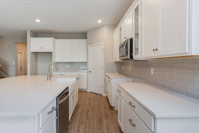 kitchen with stainless steel appliances, a sink, glass insert cabinets, and white cabinetry