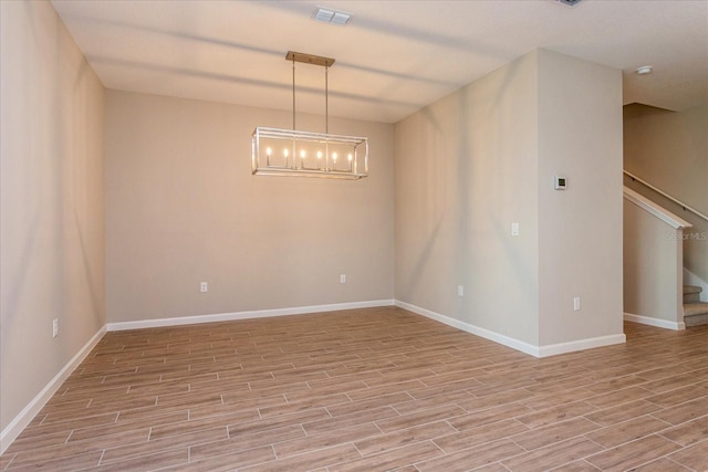 spare room featuring stairs, visible vents, light wood-style flooring, and baseboards