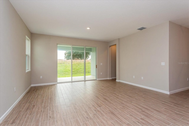 empty room featuring baseboards, visible vents, and light wood-style floors