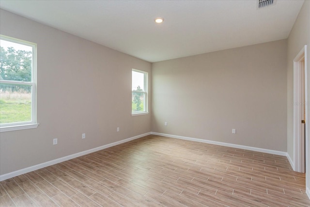 empty room with light wood finished floors, recessed lighting, visible vents, and baseboards