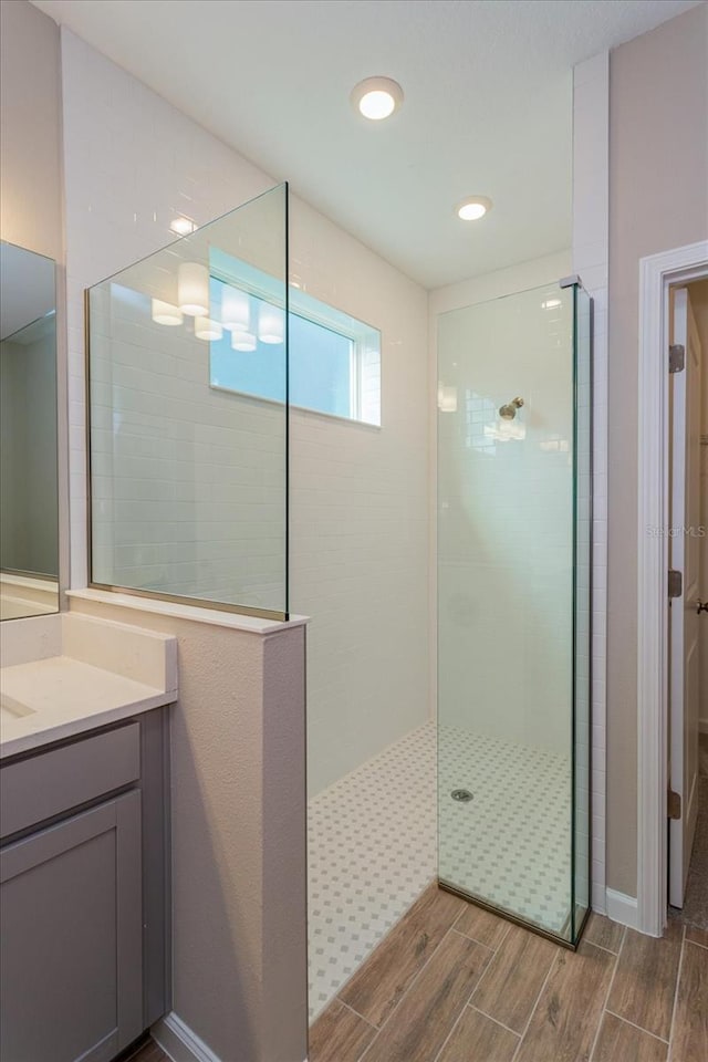 full bath with vanity, baseboards, walk in shower, and wood finish floors