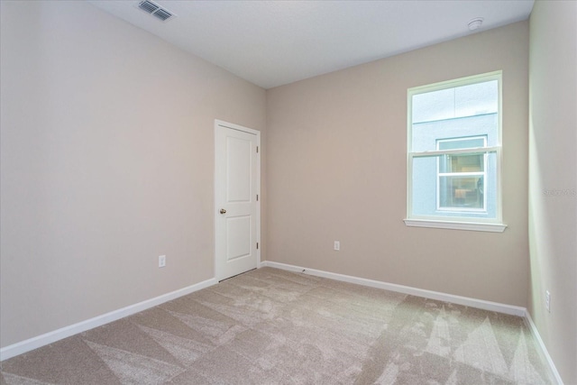 empty room featuring light carpet, visible vents, and baseboards