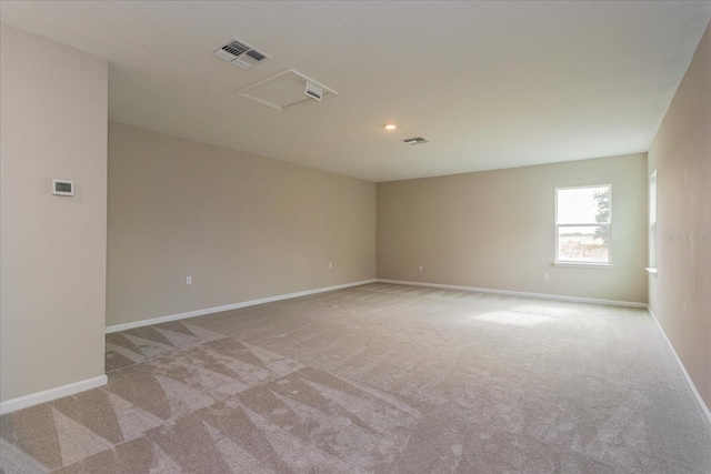 empty room featuring attic access, visible vents, light carpet, and baseboards