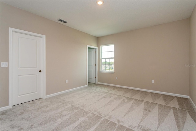 empty room featuring baseboards, visible vents, and light colored carpet