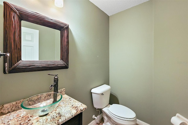 bathroom featuring vanity, a textured ceiling, and toilet