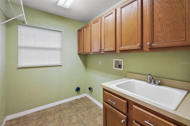 laundry area with sink, hookup for a washing machine, cabinets, and a textured ceiling