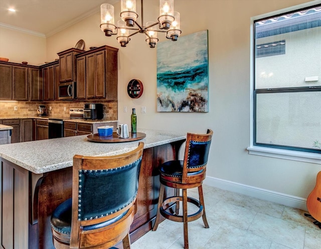 kitchen with decorative backsplash, stainless steel appliances, a kitchen bar, decorative light fixtures, and ornamental molding