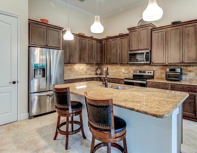 kitchen featuring pendant lighting, sink, an island with sink, appliances with stainless steel finishes, and ornamental molding