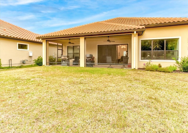 back of property with ceiling fan and a yard