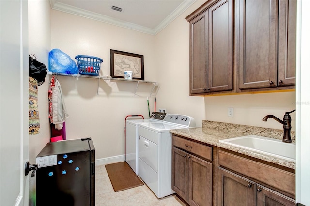 laundry room with washing machine and dryer, light tile patterned floors, cabinets, ornamental molding, and sink