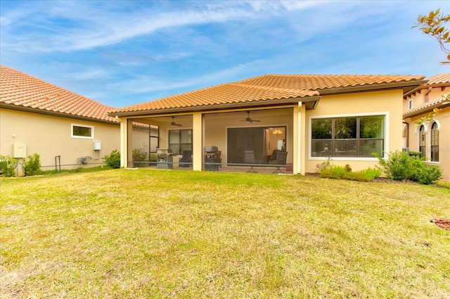 rear view of house featuring a lawn and ceiling fan