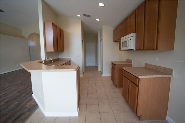 kitchen featuring lofted ceiling, sink, light tile patterned floors, and kitchen peninsula