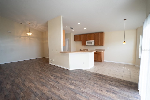 kitchen with kitchen peninsula, hanging light fixtures, and light wood-type flooring