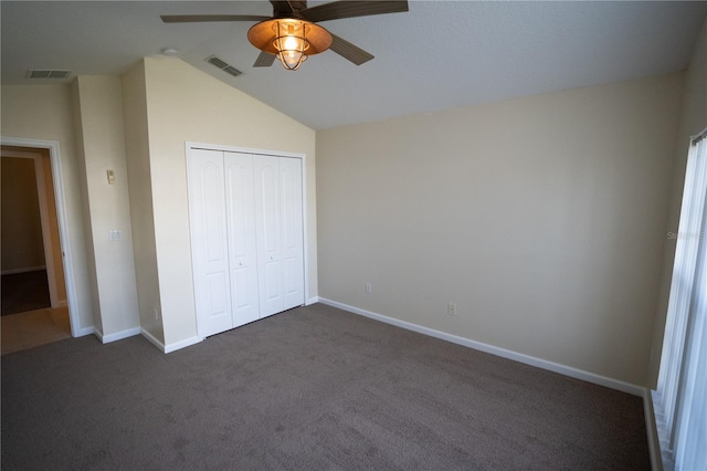 unfurnished bedroom with ceiling fan, lofted ceiling, a closet, and dark colored carpet