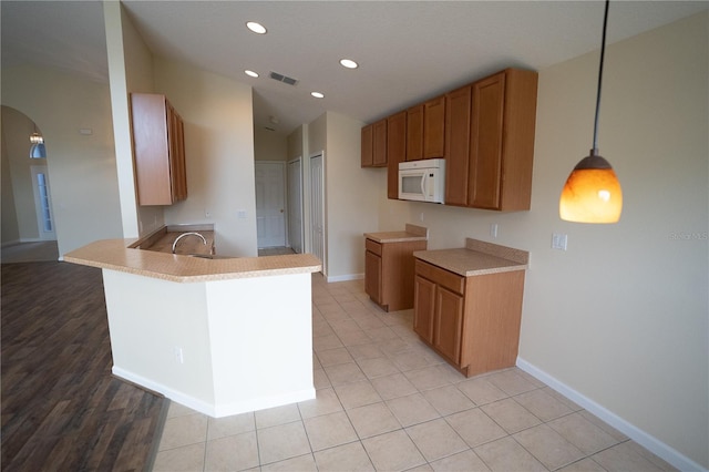 kitchen featuring decorative light fixtures, kitchen peninsula, sink, and light tile patterned floors