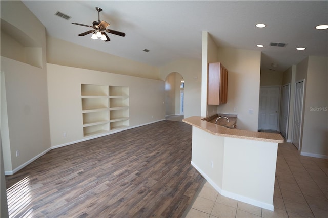 kitchen featuring built in features, lofted ceiling, ceiling fan, kitchen peninsula, and light wood-type flooring