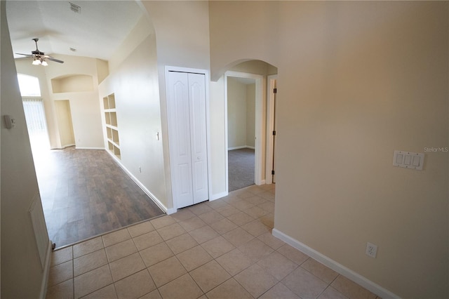 corridor with light tile patterned floors, built in features, and high vaulted ceiling