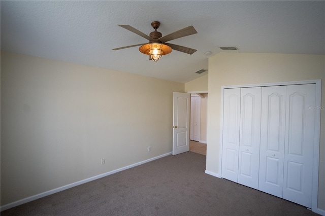 unfurnished bedroom with lofted ceiling, dark carpet, a closet, and ceiling fan