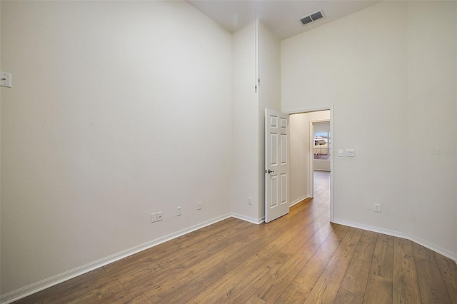 spare room with a towering ceiling and light wood-type flooring