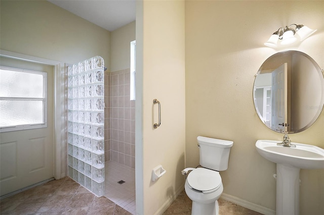 bathroom with tile patterned floors, toilet, and tiled shower