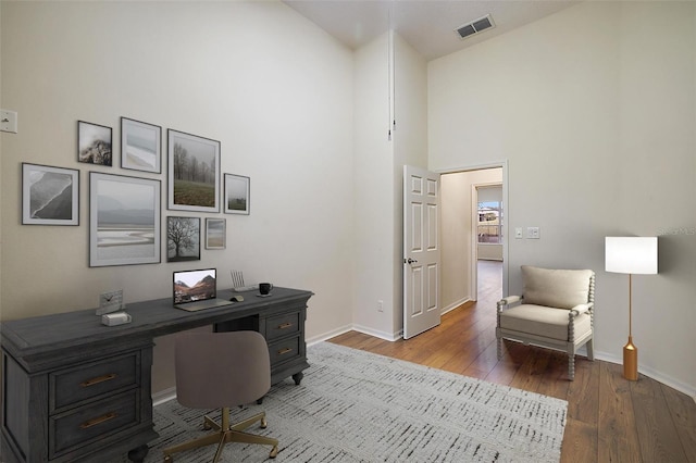 home office with hardwood / wood-style floors and high vaulted ceiling