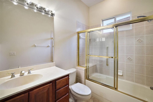 full bathroom featuring combined bath / shower with glass door, vanity, and toilet