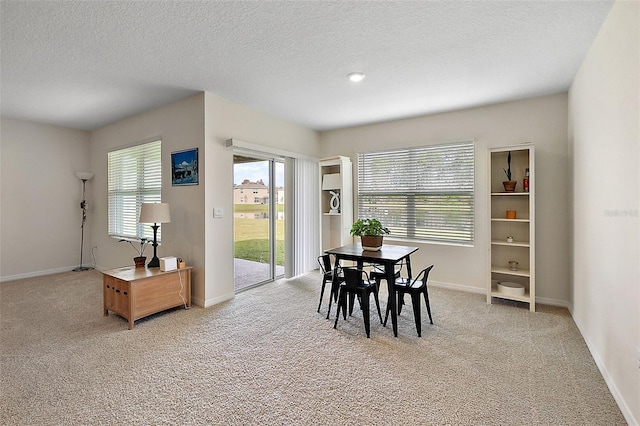 dining area with light colored carpet and a textured ceiling