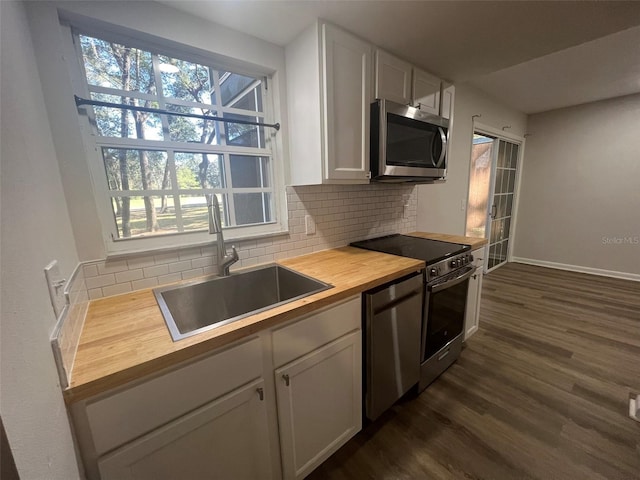 kitchen featuring backsplash, appliances with stainless steel finishes, sink, butcher block counters, and dark hardwood / wood-style flooring