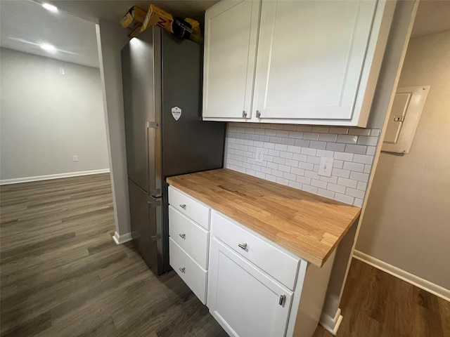 kitchen featuring dark hardwood / wood-style floors, tasteful backsplash, stainless steel fridge, and white cabinets