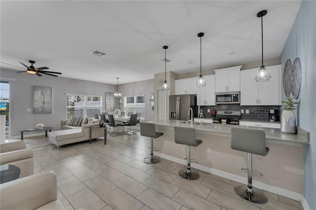 kitchen featuring a breakfast bar, appliances with stainless steel finishes, decorative light fixtures, and white cabinetry