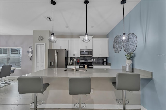 kitchen with a kitchen bar, appliances with stainless steel finishes, sink, white cabinetry, and hanging light fixtures