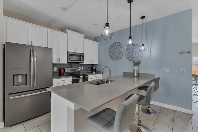 kitchen featuring decorative backsplash, appliances with stainless steel finishes, sink, pendant lighting, and white cabinets