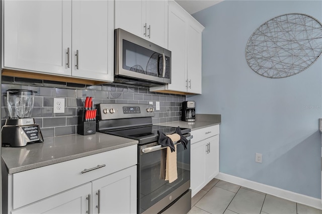 kitchen featuring light tile patterned floors, white cabinetry, appliances with stainless steel finishes, and tasteful backsplash