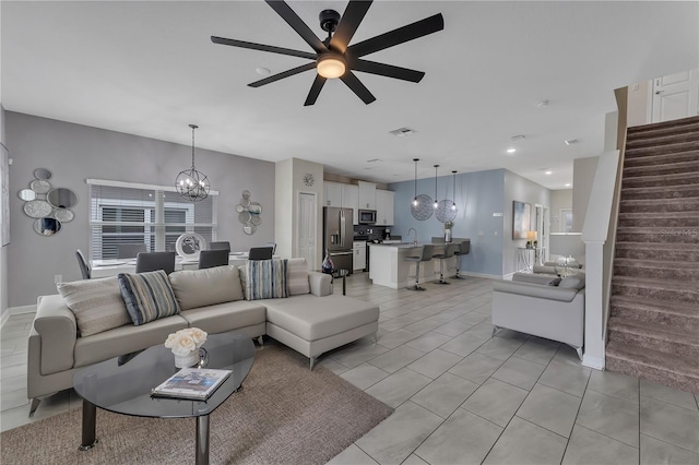 tiled living room with ceiling fan with notable chandelier and sink