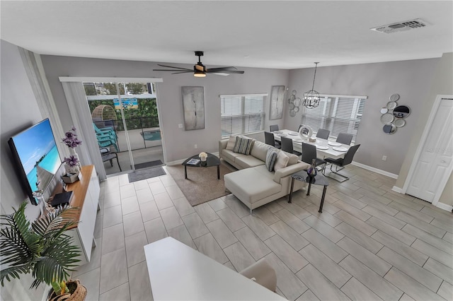 living room featuring a wealth of natural light and ceiling fan with notable chandelier