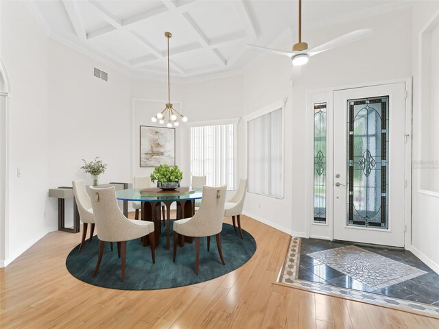 dining area featuring hardwood / wood-style floors, ceiling fan with notable chandelier, beam ceiling, and coffered ceiling