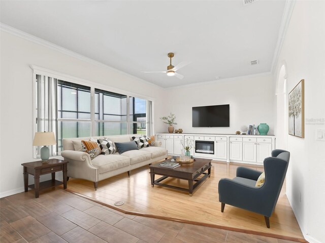 living room featuring ceiling fan, light hardwood / wood-style floors, and crown molding