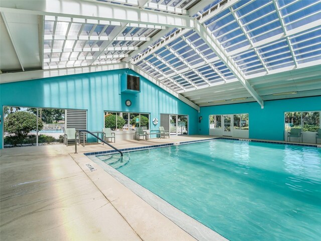 view of pool featuring glass enclosure, a patio, and exterior kitchen